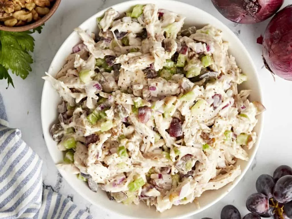 "Classic Chicken Salad: A bowl of chicken salad with chopped celery and red onion, garnished with fresh parsley"